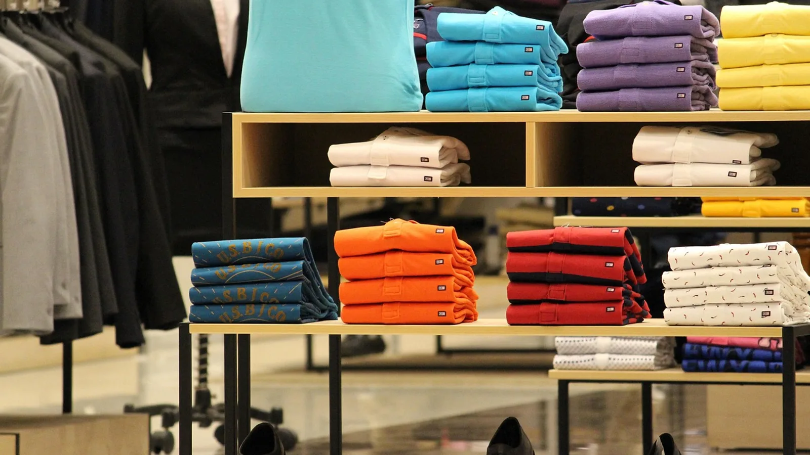 ערימות חולצות מקופלות בכמה צבעים על מדף בחנות קטנה